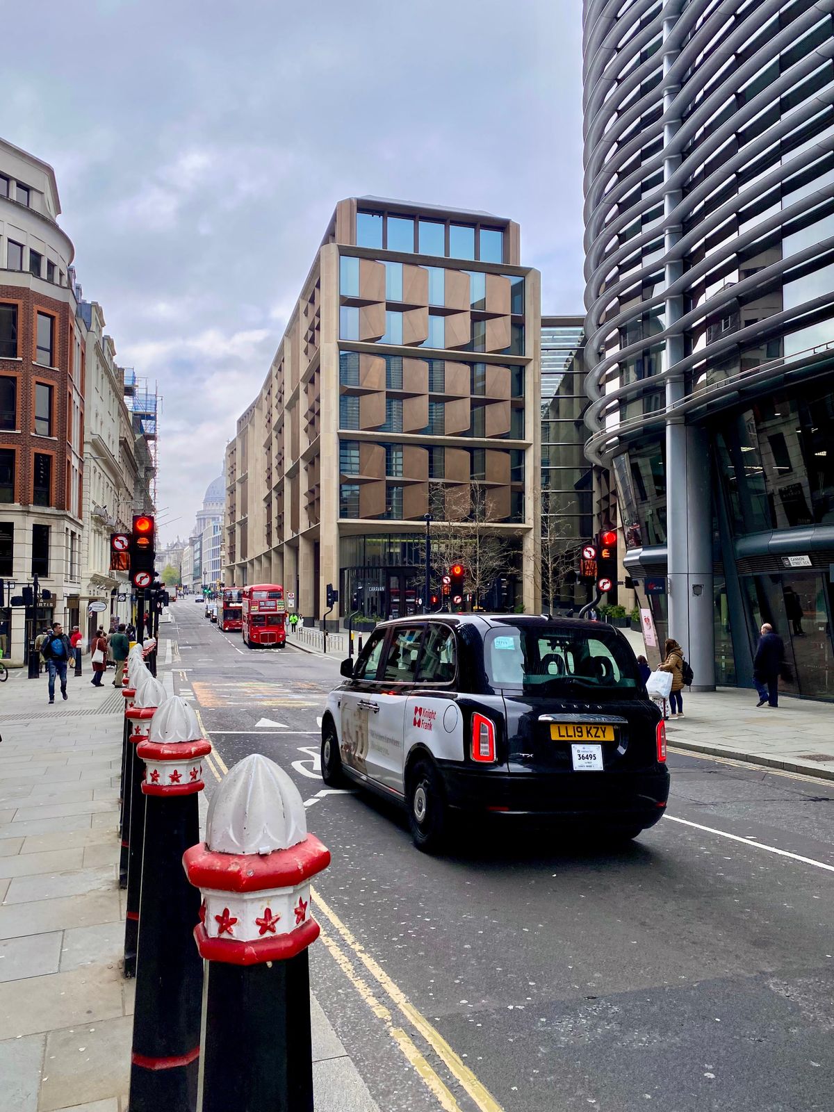 A London street with traffic and a black cab