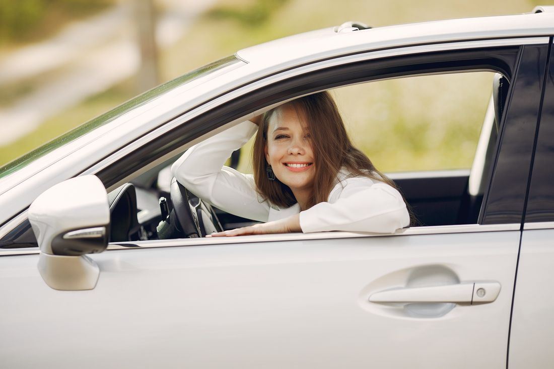 A learner smiling in the driver's seat of a white car